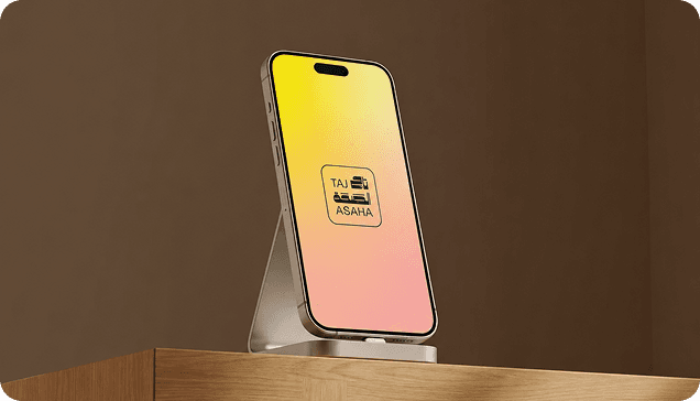 Smartphone on a stand displaying the Taj Asaha app